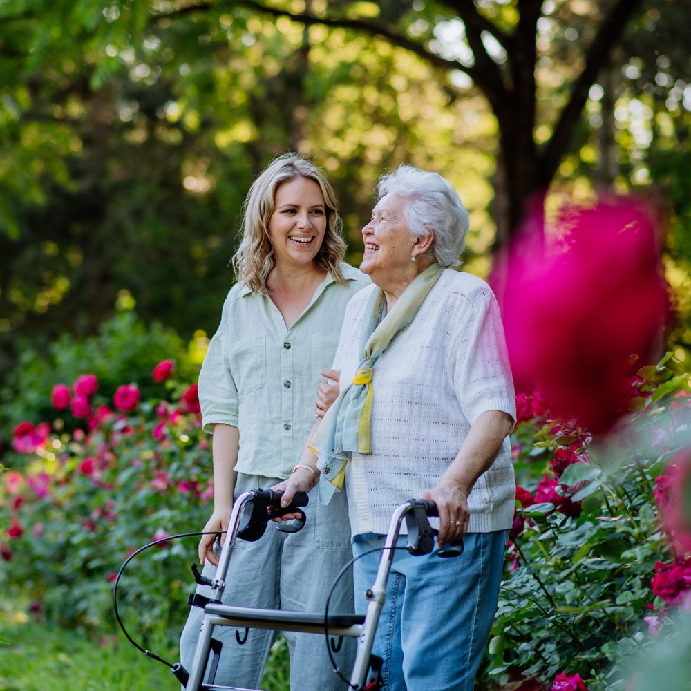 Zwei Frauen unterhalten sich herzlich in einem Rosengarten..